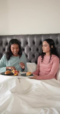 Dikey video: Afro-Amerikalı kadınlar yatakta meyve yedirme partneri, tepside meyve suyu yudumluyorlar. Samimi, samimi, samimi, yaşam tarzı, arkadaşlık, rahatlatıcı, dikey video
