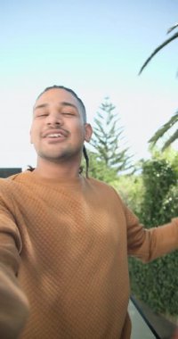 Dikey video: Balkonda kamerayı hizalayan adam yeşillik görünümüne işaret ediyor. Açık hava, yeşillik, rahatlama, iletişim, yaşam tarzı, doğa, dikey video