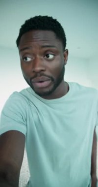 Dikey video: Afrikalı Amerikalı adam kamerayı ayarlıyor ve kameraya konuşuyor, gülümsüyor. Portre, yaşam tarzı, belgesel, samimi, sıcak, anlamlı, dikey video