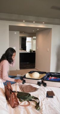 Dikey video: Yatak odasına giren bayan arkadaşlar bavullarını boşaltıyor ve gezi için kıyafet düzenliyorlar. Arkadaşlık, organizasyon, seyahat, günlük, yaşam tarzı, boş zaman, dikey video