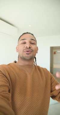 Dikey video: Bir adam vlog için yatak odasına giriyor, kamerayı ayarlıyor sonra oturuyor ve konuşuyor. İçerik oluşturucu, vloglama, modern iç mekan, günlük yaşam tarzı, minimal tasarım, etkili, dikey video