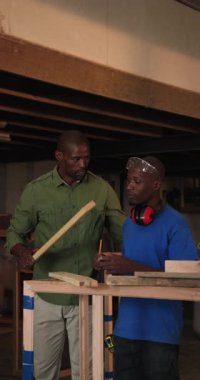 Dikey video: Afro-Amerikan akıl hocası ve çırak atölyede hizalanmak için kalem hattını takip ediyorlar. Sanatçılık, zanaat, eğitim, hassasiyet, araçlar, inşaat, dikey video