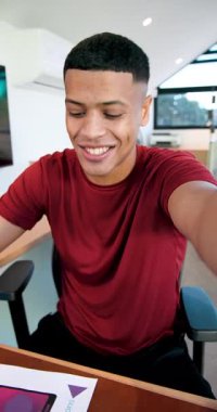 Dikey video: Çekimlerden sonra Afrikalı Amerikalı bir adam masada konuşuyor ve şablonları gözden geçiriyordu. Profesyonel, yaratıcı, modern, dijital, çalışma alanı, enerjik, dikey video