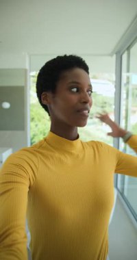 Dikey video: Afro-Amerikan kadın dairede telefonla balkon, banyo ve yatak odasını gösteriyor. Modern, yaşam tarzı, minimalizm, şehir, rahatlama, güven, dikey video
