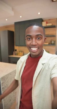 Dikey video: Akıllı telefon montajlı Afro-Amerikan adam izleyicileri karşılıyor mutfak adasını gösteriyor. Modern, minimalist, iç mekan, yaşam tarzı, markalı, sinematik, dikey video