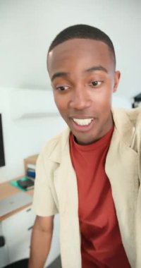 Dikey video: Afrika kökenli Amerikalı bir adam ofiste oturmuş el sallıyor ve büyüme ölçülerini vurguluyor. Teknoloji, iş dünyası, analitik, sunum, yenilik, modern, dikey video