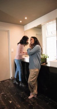 Dikey video: Afro-Amerikalı kadın arkadaşlar sabah rutinine başlıyorlar ve lavaboya makyaj yapıyorlar. Arkadaşlık, kişisel bakım, güzellik, tımar, günlük yaşam tarzı, dikey video