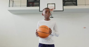 Spor salonunda basketbol oynayan Afrikalı Amerikalı çocuk kararlı ve odaklanmış görünüyor. Sporcu, spor, kararlılık, gençlik, spor salonu, fitness