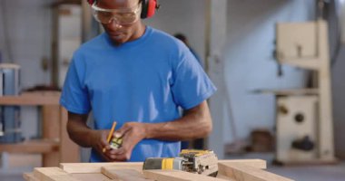 Afro-Amerikalı iş arkadaşları sarı yapboz ve güvenlik gözlükleri ile tezgah kesiyorlar. Kopya alanı. El işi, takım çalışması, endüstriyel, ahşap işçiliği, güvenlik, el işçiliği, profesyonel