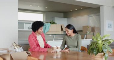 Çeşitli çiftler yemek masasında kutuları taşırken, kahve içerken yeni evleri keşfediyorlar. Modern, rahat, minimalist, yaşam tarzı, evcil, neşeli, sıcak