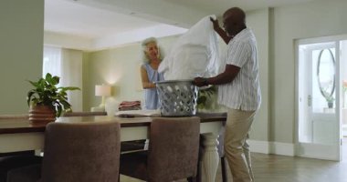 Üst düzey bir çift yemek alanında çamaşır sepeti taşıyor çarşafları katlıyor ve katlıyor, fotokopi çekiyor. Yurt içi bakım, işbirliği, uyum, minimalizm, rutin, ev dekorasyonu