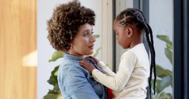 Farklı anne ve kızları kapıda sarılıyor, ceketi okşuyor, gülüyor ve dışarıyı işaret ediyor. Sevgi, aile, şefkat, bağlantı, bağ, mutluluk, sıcaklık