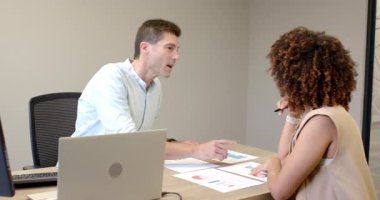 Yazılı çizelgeleri yerleştiren ve ofisteki veri incelemesi sırasında dizüstü bilgisayara işaret eden çeşitli iş arkadaşları. İşbirliği, analitik, sunum, çalışma alanı, profesyonel, takım çalışması, dijital