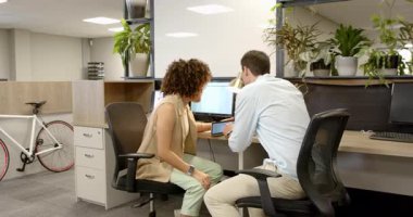 İş arkadaşına katılan, tableti tıklatan, grafik trendlerini tartışan monitörleri gösteren bir adam. İşbirliği, teknoloji, şirket, profesyonellik, veri analizi, çalışma alanı, iletişim