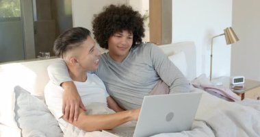 Dizüstü bilgisayar açmak, çeşitli erkek partnerler kollarını sarmak ve yatakta gülmek için pist üzerinde gezinmek. Romantik, samimiyet, bağlantı, eğlence, rahatlık, gündelik, sevgi dolu.