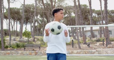 Sahada futbol topu tutan çocuk, dışarıda antrenman yaparken kararlı görünüyor, fotokopi alanı. Spor, kararlılık, gençlik, atlet, egzersiz