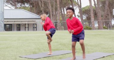 Okul sahasında yoga yapan çok ırklı çocuklar, okul aktivitelerine odaklanıp denge sağlıyorlar. Farkındalık, egzersiz, konsantrasyon, esneklik, sağlık, çok ırklı çocuklar