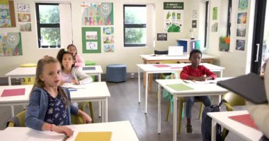 Sınıfta, çeşitli öğrenciler el kaldırıyor, geri dönüşüm derslerine katılıyorlar. Sürdürülebilirlik, eğitim, çeşitlilik, çevre, öğrenme, katılım