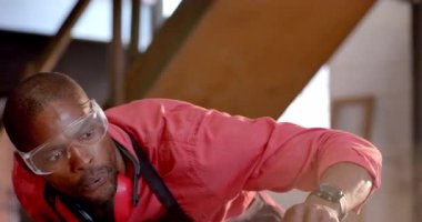 Gözlük takan Afro-Amerikalı bir adam tezgahta zımpara bloğu kullanıyor, mavi kıskaçları var. Zanaatkar, tamirci, atölye, yenileme, işçilik, mekanik, zanaatkar