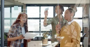 Çeşitli kadın takımlar kodlama projesinde işbirliği yapıyorlar, modern ofiste cam tahtaya yazı yazıyorlar. İşbirliği, takım çalışması, beyin fırtınası, yenilik, teknoloji, yazılım geliştirme