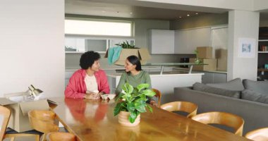 Afrika kökenli Amerikalı ve Hintli çiftler dairelerine yerleşirken planları gözden geçirip mobilyaları yerleştiriyorlar. İşbirliği, ev, modern, iç mekan, yaşam tarzı, planlama, tasarım