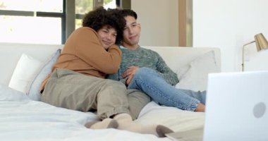 İki adam evde yatakta gümüş dizüstü bilgisayar açıyor ve ekranın içeriğine gülerken sarılıp yatıyorlar. Romantizm, samimiyet, rahatlama, konfor, arkadaşlık, yaşam tarzı, modern