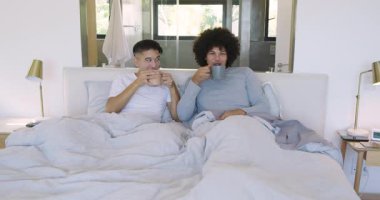 Güneş ışığı pencereden neşe saçıyor, iki adam kahvelerini yudumluyor ve yatakta battaniyeye sarılıyorlar. Samimiyet, şefkat, bağlantı, rahatlık, rahatlık, samimiyet, sıcaklık.