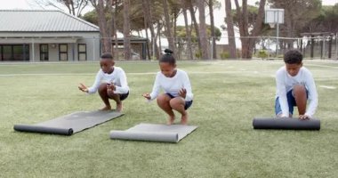 Okul bahçesinde paspaslar üzerinde denge alıştırması yapan çok ırklı öğrenciler. çok ırklı öğrenciler, açık hava aktivitesi, takım çalışması, koordinasyon, spor, oyuncu