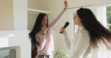 Yumuşak müzik karaokeyi işaret ediyor, çeşitli bayan arkadaşlar oturma odasında kablosuz mikrofonlara şarkı söylüyorlar. Eğlence, dostluk, eğlence, hayat dolu, neşeli, sosyal, gençlik dolu.