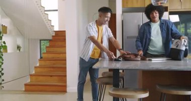 Çeşitli erkek arkadaşlar içeri giriyor, mutfak adasına iniyor, akıllı telefonu paylaşıyor, gülüyorlar. Arkadaşlık, gündelik, modern, iç mekan, iletişim, yaşam tarzı, bağlantı