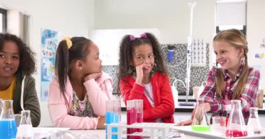 Fen derslerinde test tüpleriyle gülümseyen öğrenciler, birlikte öğrenmenin tadını çıkarıyorlar. Eğitim, sınıf, deney, takım çalışması, merak, öğrenciler