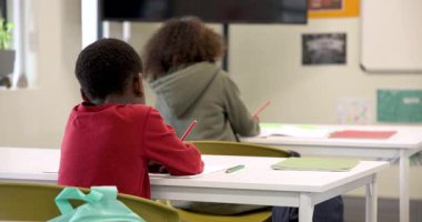 Sınıfta elinde kalemle gülümseyen çocuk, öğrenme aktivitelerinden zevk alıyor, kopyalama alanını kullanıyor. Eğitim, öğrenim, çocukluk, mutluluk, yaratıcılık, okula dönüş