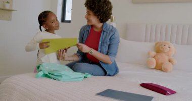 Çeşitli anne ve kız çocukları kırmızı klasörü çekiyor, dosyaları topluyor ve yatak odasındaki okul çantasına koyuyorlar. Aile, eğitim, öğrenme, yetiştirme, çocukluk, organizasyon, pozitiflik