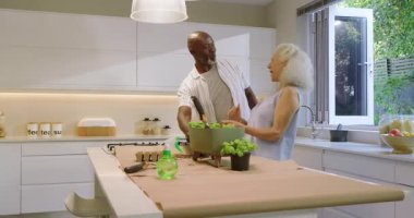 Yaşlı çiftin mutfakta fesleğen tohumu ektiği kraft kağıdıyla adayı kaplıyor. Bitkiler, bahçıvanlık, işbirliği, sağlık, doğal yaşam, ev, modern