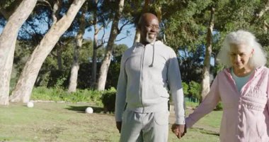 Farklı yaşlı çiftler park ışıklarının önünden geçerek ağaçta duran akıllı telefonları kontrol ediyorlar. Yaşlılar, yoldaşlar, eğlence, doğa, uyum, rahatlama, açık hava.