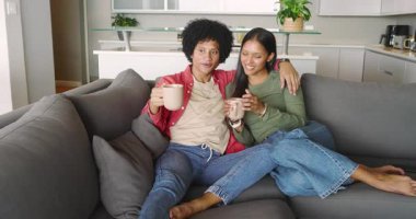 Gri kanepede fincanlardan yudumlayan, çeşitli çiftler mutfaktaki saksı bitkisine hayran ve işaret ediyorlar. Romantizm, rahatlama, arkadaşlık, ev içi, günlük yaşam tarzı, duygusal bağlantı, sıcak ortam.