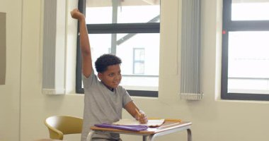 Sınıfta, çocuk elinde defterle masada oturuyor, düşünceli görünüyor, okulda. Eğitim, öğrenme, düşünme, düşünme, okul, öğrenci