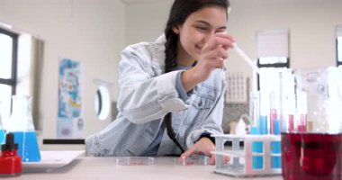 Fen sınıfındaki kız petri kabıyla pipet kullanıyor, okulda deneylere odaklanmış. Laboratuvar, araştırma, eğitim, kimya, biyoloji, elden ele çalışma