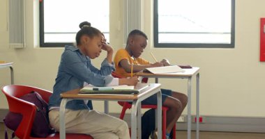 Sınıftaki çok ırklı öğrenciler not defterlerine yazarak okul ödevlerine odaklandılar. Eğitim, öğrenim, öğretim, öğretim