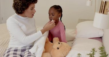 Anne kızını yatakta rahatlatıyor, termometreyi tarıyor, battaniye sokuyor, doktor çağırıyor. Bakım, bakım, sıcaklık, sağlık, aile, samimiyet, güven