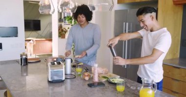 Ekmek yağlayan iki adam, mutfak adasında sebze tatlandırıp yumurta kırarak birbirlerine sarılıyorlar. Yemek, kahvaltı, samimiyet, takım çalışması, modern, neşeli, aile