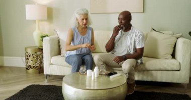 Yaşlı çift ilaç şişesi veriyor, ilaç koyuyor su bardaklarını tıkırdatıyor, dozajı açıklıyor. Bakım, arkadaşlık, sağlık, refah, olgunluk, destek, yaşam tarzı