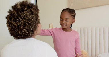 Afrika kökenli Amerikalı anne ve kız makyaj malzemelerini fotokopi odasında sunmaya başlıyorlar. Bağ, beslenme, şefkat, yakınlık, çocukluk, bakım, rahatlık