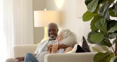 Oturma odasındaki bej kanepede gülen çeşitli çiftler, saçlarını kıvıran adamı işaret ediyor. Şefkat, arkadaşlık, sıcaklık, rahatlama, samimiyet, ev, yaşam tarzı.