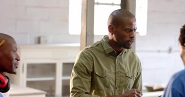 Parlak oturma odasında Afro-Amerikalı arkadaşları tartışıp şömine ve pencerenin yanında el kol hareketi yapıyorlar. İşbirliği, tartışma, iç mekan, modern, iletişim, çeşitlilik, gelişigüzel