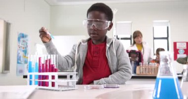 Fen dersinde deney tüpleri takan, güvenlik gözlüğü takan bir öğrenci. lab, kimya, araştırma, eğitim, laboratuvar ekipmanları