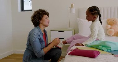 Anne ve kız yataklarında diz çöküp spor ayakkabılarını bağlıyor ve okul için nane yeşili sırt çantası hazırlıyorlar. Bakım, bakım, hazırlık, çocukluk, aile, eğitim, sıcaklık