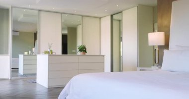 Başlangıç kamerasında soldaki lamba, şifonyer, dolap kapıları yatak odası düzenini gösteriyor. Modern, minimalist, zarafet, uyum, rahatlama, iç mekan, dekor