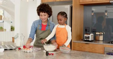 Çeşitli anne ve kız çocukları yumurta kapıyor, hamuru çırpıyor, adada krep hamuru için vanilya ekliyor. Aile, bakım, evcil, el yapımı, rahat, besleyici, aşçı