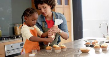 Çeşitli anne ve kız kekler üzerinde şekerleme yapıyor, ana rehber kız tezgahta tadımlık yapıyor. Aile, pişirme, yaratıcılık, beceri geliştirme, beslenme, ev yemekleri, sıcaklık